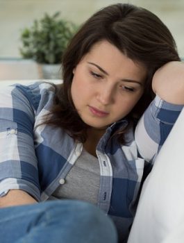Young concerned woman sitting on psychologist's couch